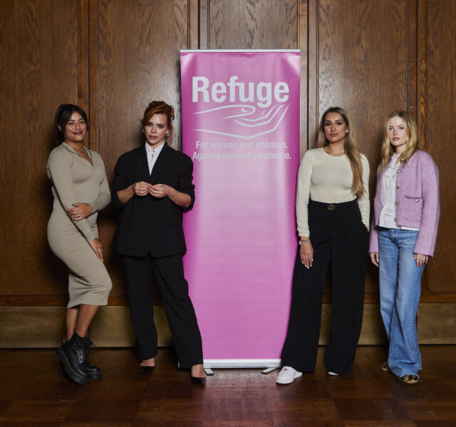 Four women standing in front of a pink Refuge branded banner