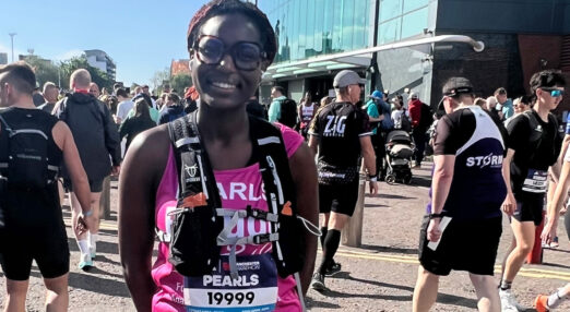 Woman wearing Refuge branded vest and running gear smiles at camera with runners around her