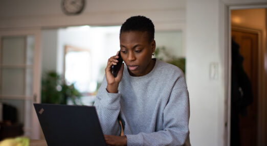Woman on the phone and looking at a laptop.