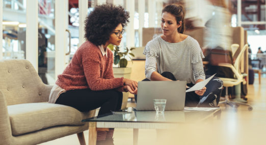 Image of two women sat next to a laptop talking