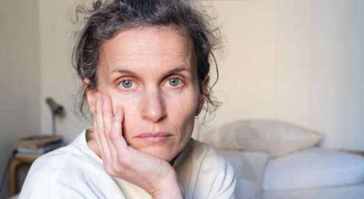 Image of a woman looking directly into the camera leaning on her hand