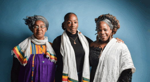 Three members of Sistah Space smiling at the camera with arms round each other